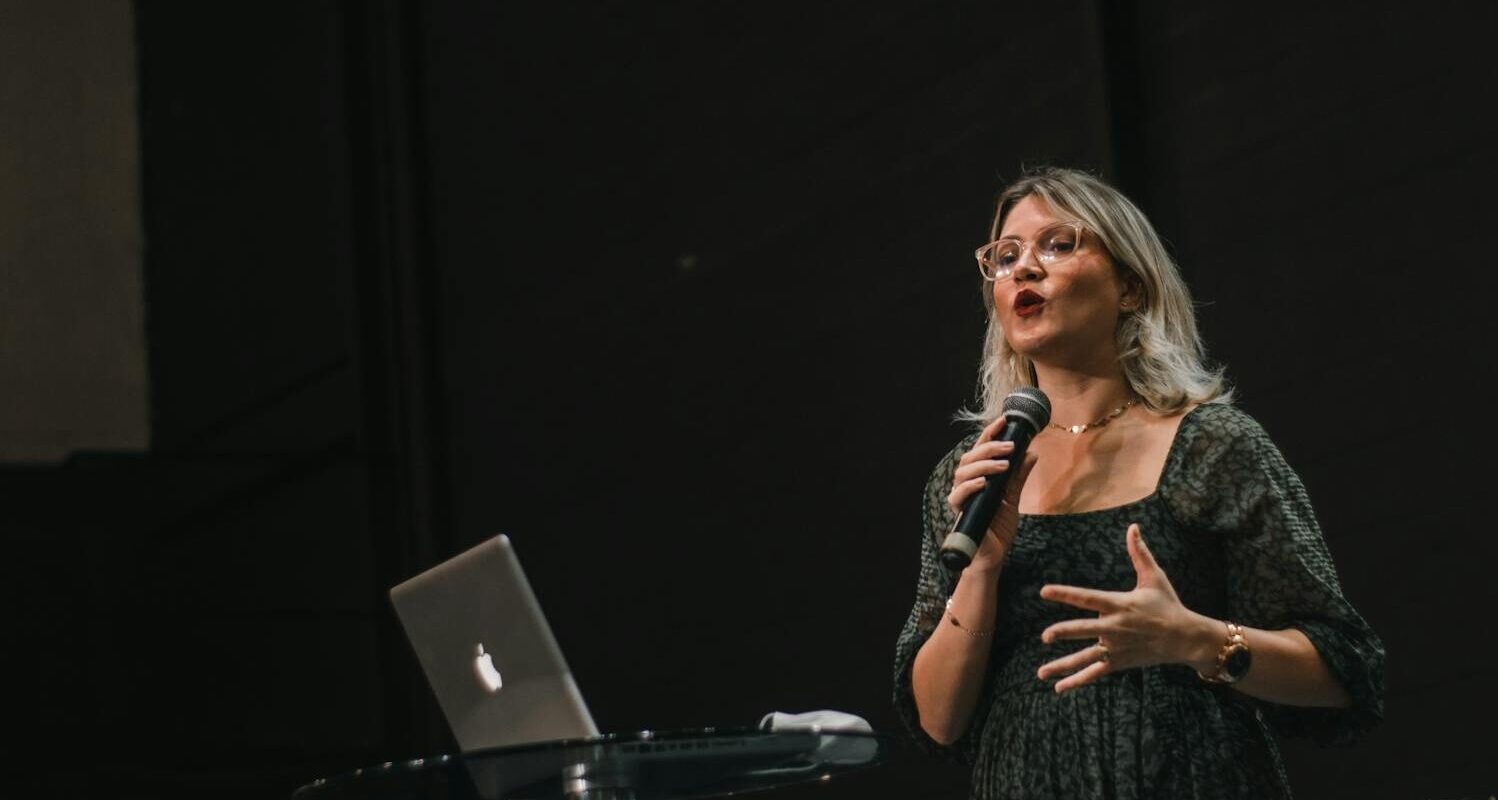 woman with microphone speaking on stage